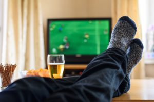 Television, TV watching (football match) with feet on table and huge amounts of snacks - stock photo